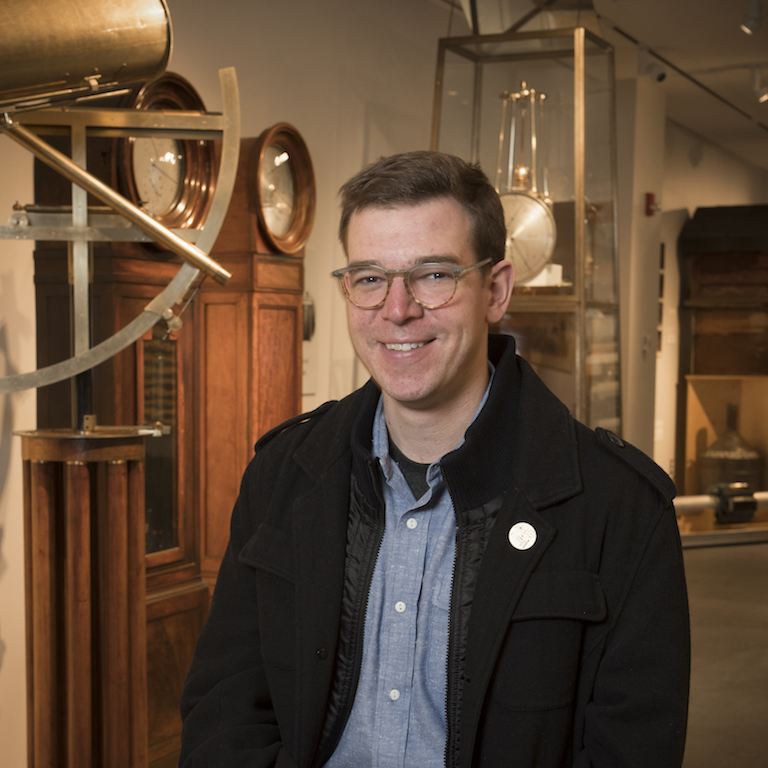 Evander Price posing for a photo in front of an exhibit